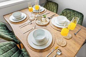 A dining table set with white plates, bowls, cutlery, and glasses of orange juice. - Spacious 4 Bed Home | Free Parking & Fast WiFi (Denton)