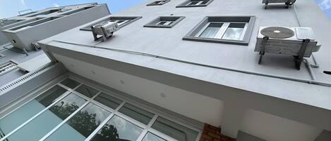 Un bâtiment moderne doté de plusieurs unités de climatisation, de grandes fenêtres et d’un toit plat.
