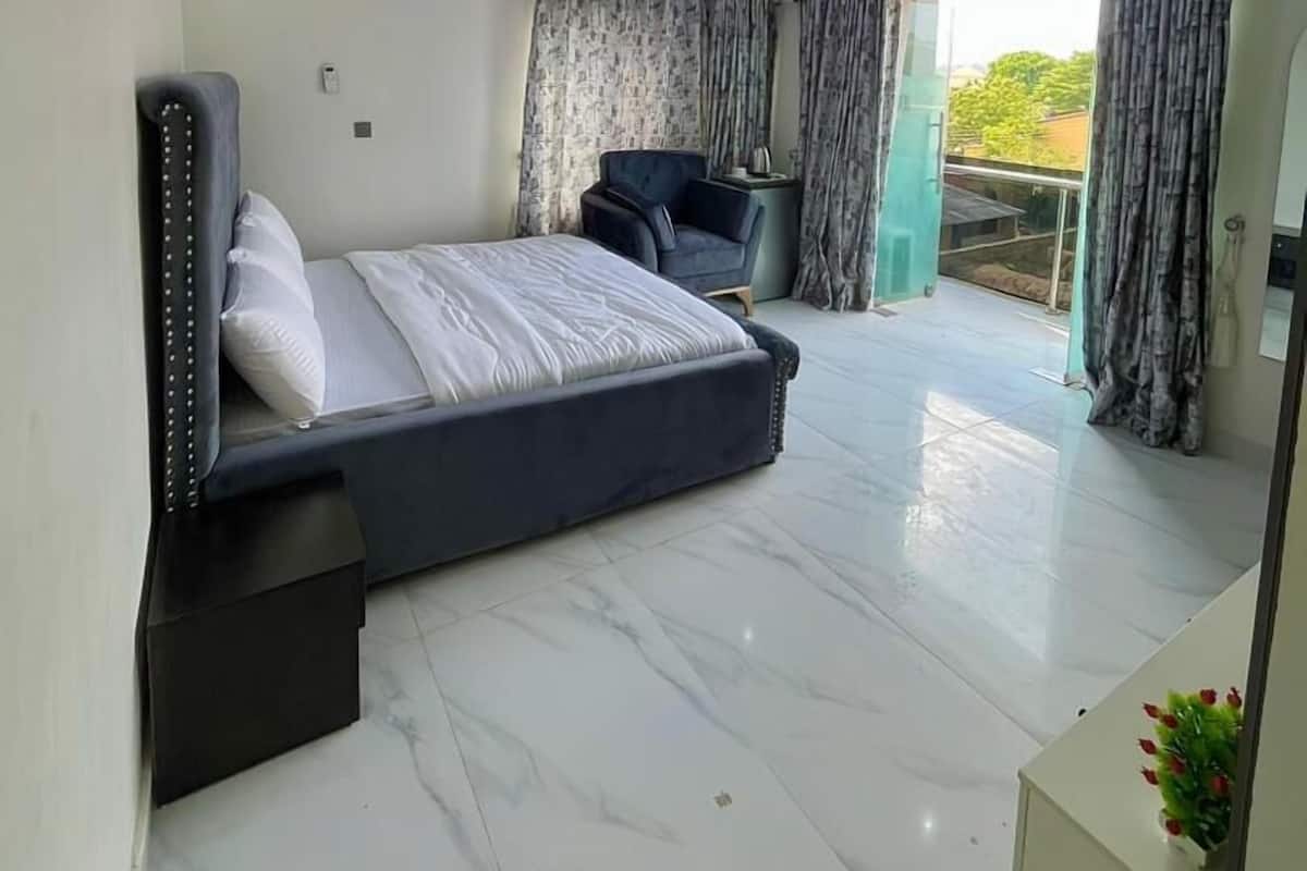 Un dormitorio moderno con una cama grande, una zona de estar y un balcón con cortinas.