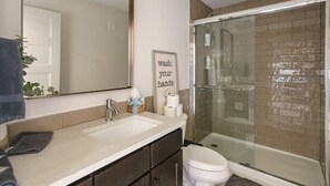 Een moderne badkamer met een grote spiegel, een wastafel, een toilet en een douchecabine.
