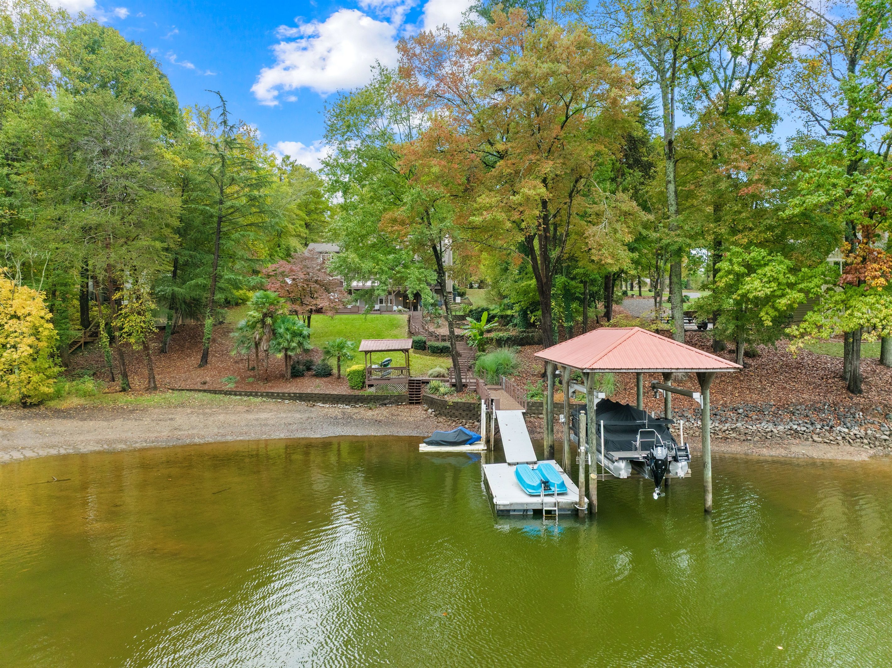 Un paisaje tranquilo junto al lago, con un pabellón, un muelle y un bote pequeño.