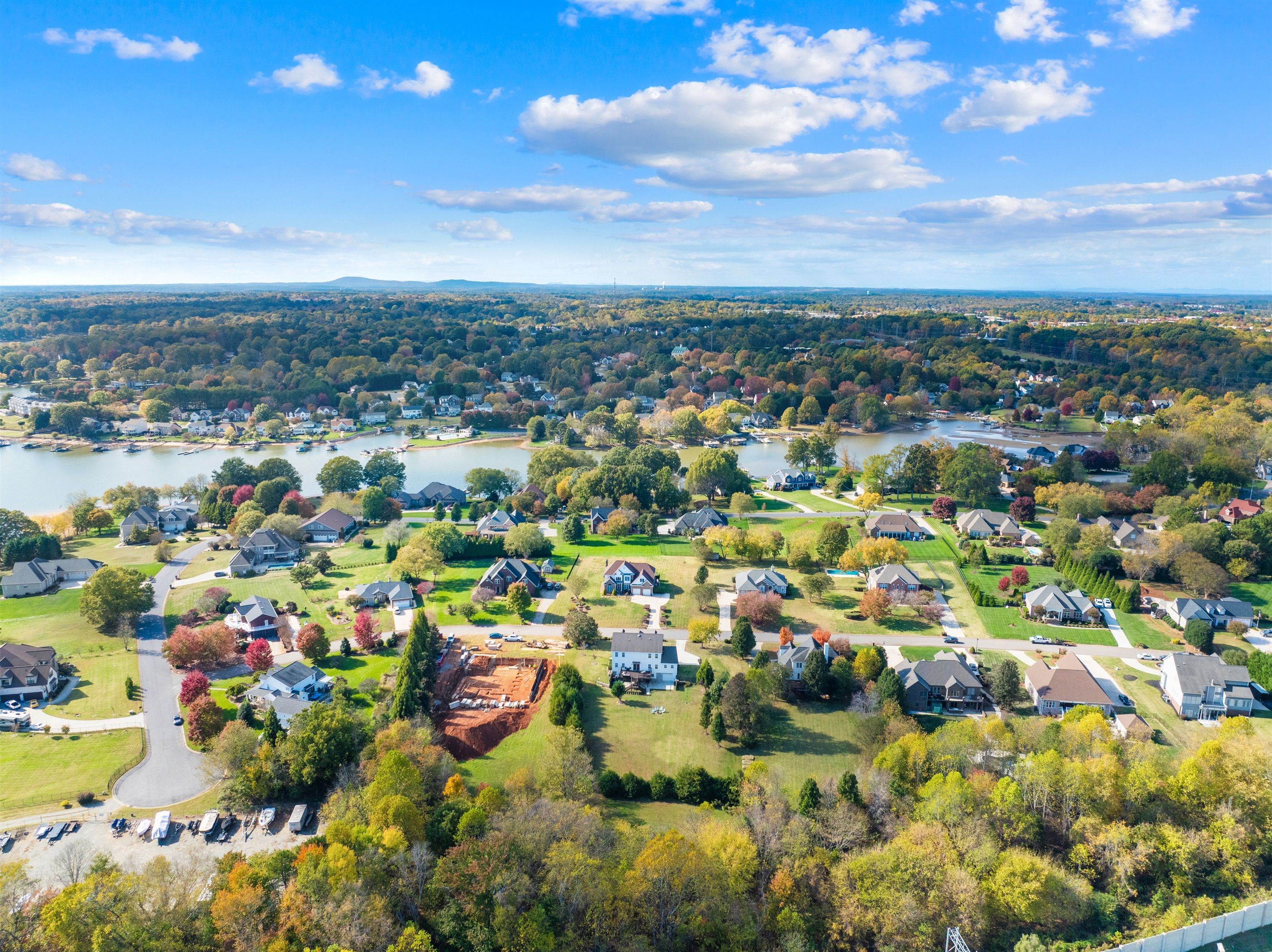 An aerial view of a residential area with houses, a lake, and a park.