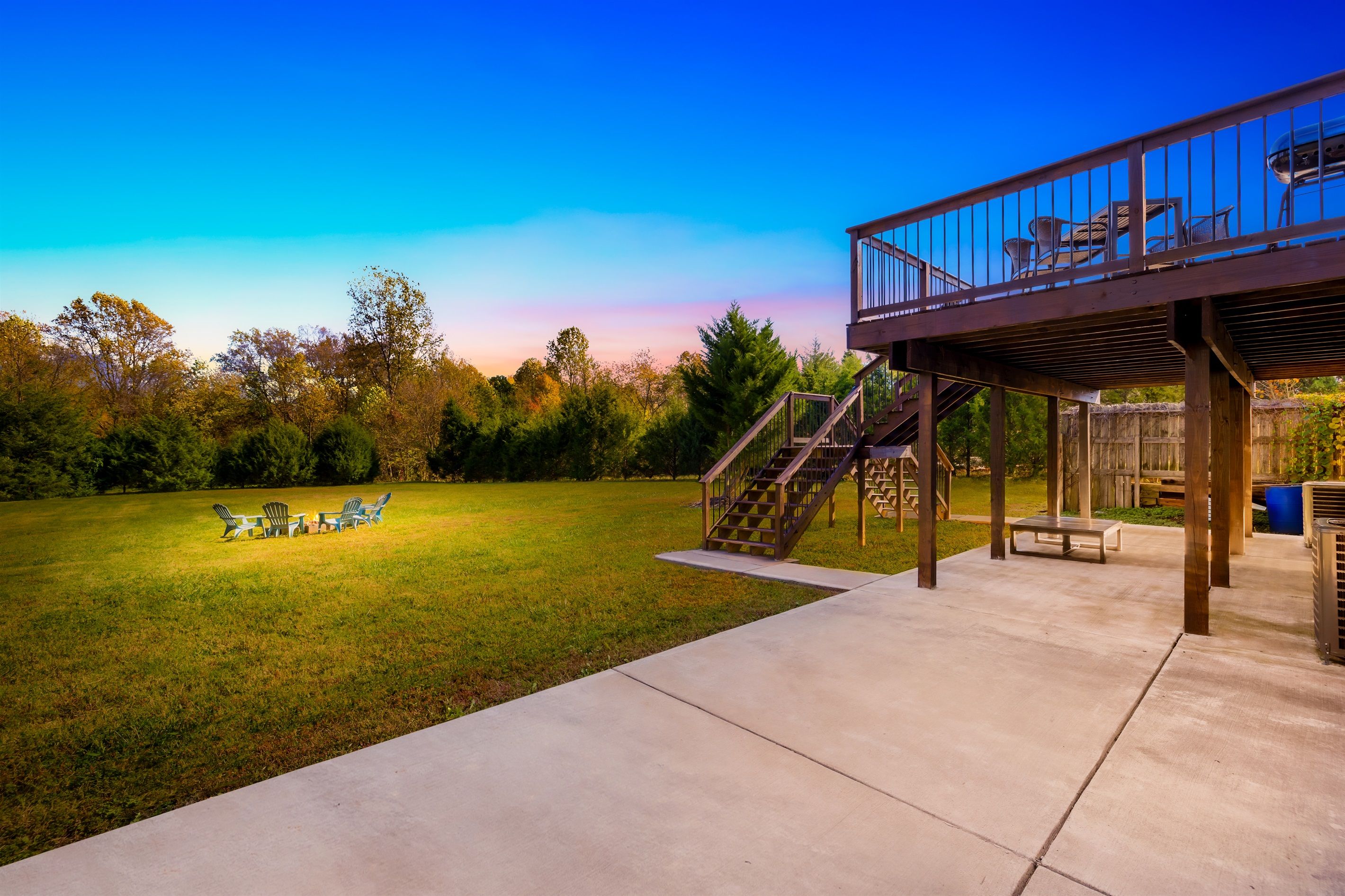 Ein Garten mit überdachter Terrasse, Sitzgelegenheiten im Freien und einer Treppe zu einer Holzterrasse.