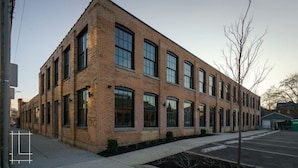 A multi-story brick building with large windows and a parking lot in front. - Spacious Industrial Flat - Short North (Columbus)