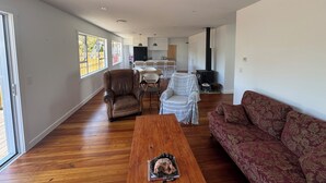 Un salon spacieux avec une table basse en bois, un canapé à motifs et un coin repas comprenant des chaises et une table.