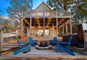 A wooden deck with a fire pit and blue Adirondack chairs. - Peaceful Lakeside Escape with Dock & Hot Tub (Hot Springs)