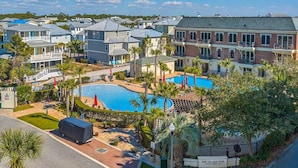 Zona residencial con piscina rodeada de casas y palmeras.