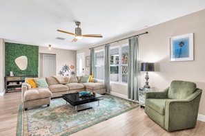 A living room with a sectional sofa, a green armchair, a coffee table, and a patterned rug. - BOAT LIFT! Waterfront Home w/ Hot Tub & Fire Pit! (Palm City)