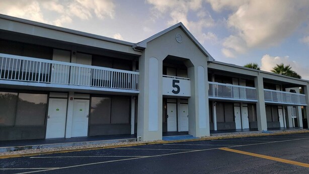 Um motel com uma placa de número 5, várias varandas e um estacionamento.