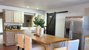 Une cuisine moderne avec des plans de travail en bois, des meubles blancs et un îlot central doté de chaises.