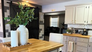 Une cuisine avec un plan de travail en bois, des armoires blanches et une porte noire.