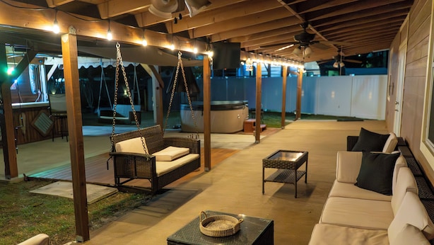 Une terrasse extérieure avec une balançoire, un canapé et une table basse.