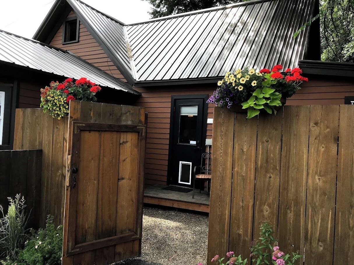 A wooden house with a metal roof, a front door, and a small porch.
