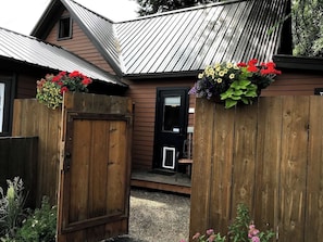 Una casa de madera con techo de metal, una puerta principal y un porche pequeño.