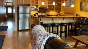 Une cuisine moderne avec des meubles en bois, un réfrigérateur en acier inoxydable et un coin bar équipé de tabourets.