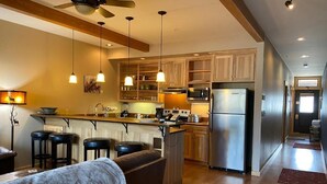 Une cuisine moderne avec des meubles en bois, des appareils électroménagers en acier inoxydable et des luminaires suspendus.