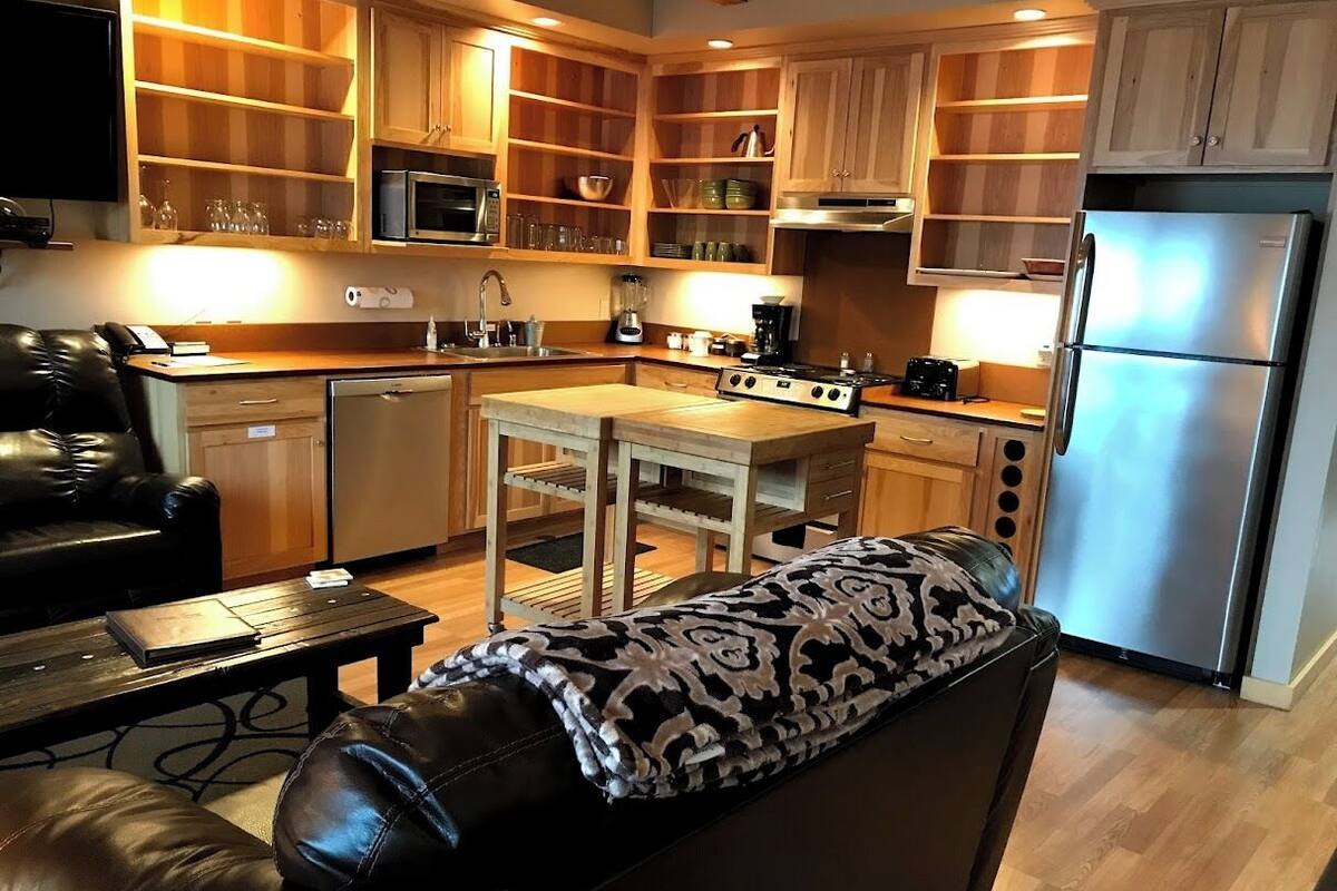 A compact kitchen with wooden cabinets, a built-in microwave, a stove, and a refrigerator.
