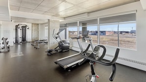 Une salle de sport équipée de tapis de course, de vélos elliptiques et de matériel de musculation.