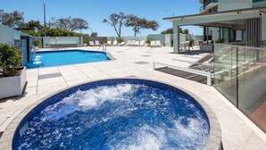 Een zwembad op het dak met een jacuzzi, ligbedden en een overdekte zitgedeelte.