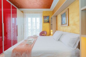 Una habitación de hotel con cama, una silla, ventana con cortinas y un cuadro en la pared.