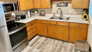 A kitchen with wooden cabinets, stainless steel appliances, a sink, and a decorative wall piece. - Cozy-Comfortable Linden Retreat (Idaho Falls)
