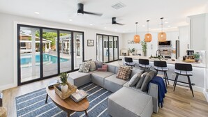 Un salon moderne avec un canapé d’angle, une table basse et une vue sur une piscine extérieure.