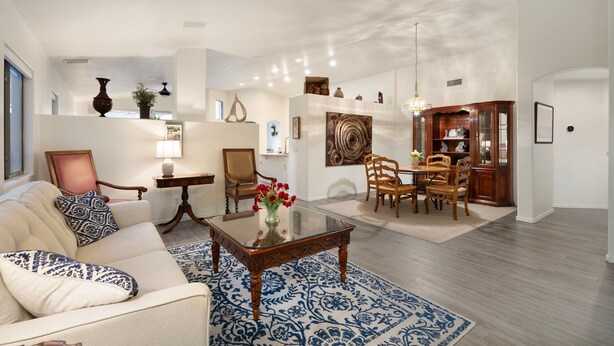 A spacious living room with a sofa, coffee table, and dining area with chairs and a wooden cabinet. - Desert Retreat w/ Pool, Trails & Mountain Views (Mesa)