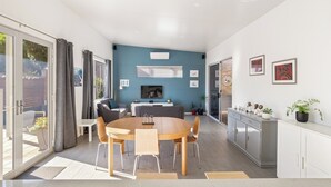 Un espacio habitable moderno con comedor, cocina y un amplio ventanal corredera que da a un balcón.