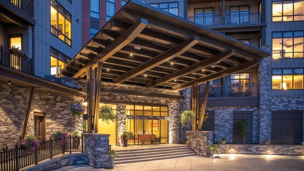 A hotel entrance with a covered patio, stone facade, and multiple balconies. - Experience Mountain Luxury and Family Fun at Wyndham Resort at Avon- 2 Bd. Pres (Avon)