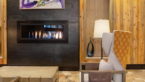A modern interior with a fireplace, a painting, a lamp, and a wicker chair. - Experience Mountain Luxury and Family Fun at Wyndham Resort at Avon- 2 Bd. Pres (Avon)