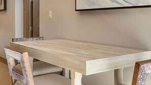 Une table de salle à manger rectangulaire avec un placage en bois clair, accompagnée de quatre chaises au design vieilli.