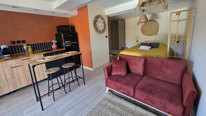 Un espacio habitable moderno con cocina, comedor y una cama grande con un sofá rojo.