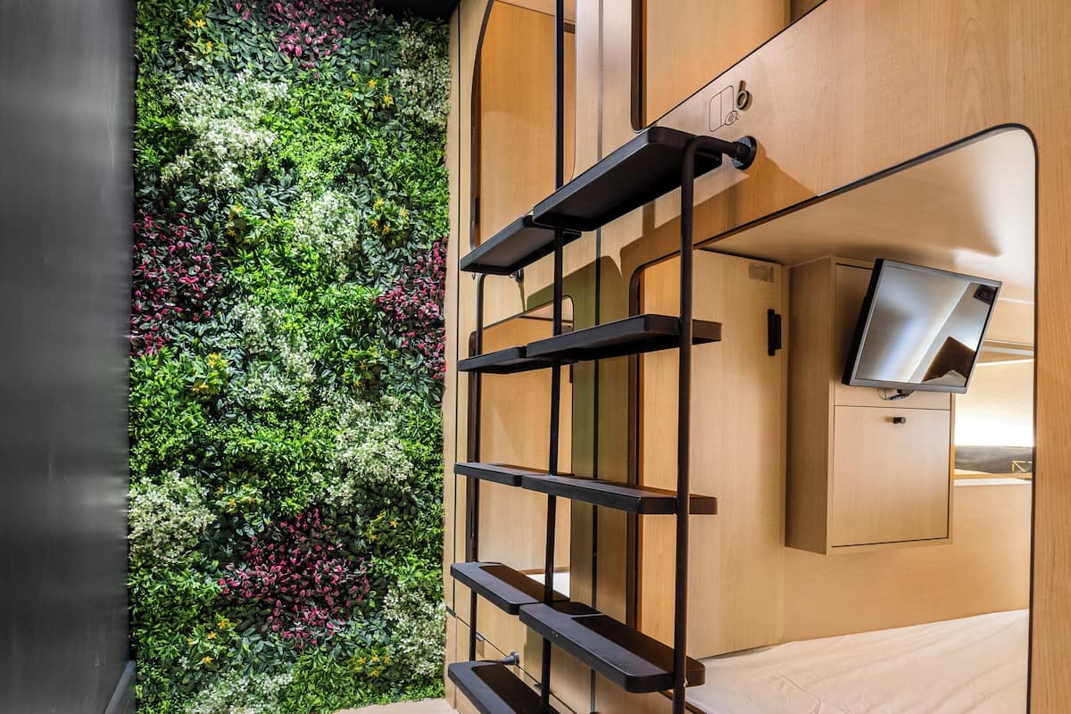 A modern interior with a wooden wall, a mounted TV, and a green vertical garden.