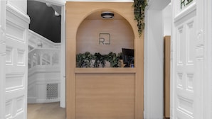 Zona de recepción con mostrador de madera, un escritorio y un letrero con la letra 'R'.
