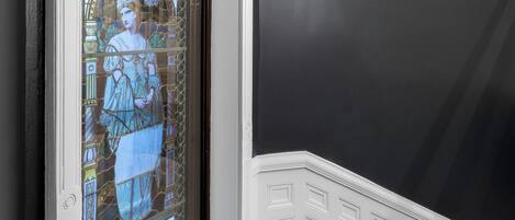 Uma porta de vitrais com desenhos elaborados, moldura branca e parede escura.