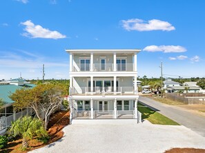 A two-story building with a balcony on the upper floor, a covered front porch, and a number '200' on the facade. - Sandy Feet Retreat | 8BR | Gulf View Escape! Private Pool & Spa! Walk to Beach! (mexico beach)