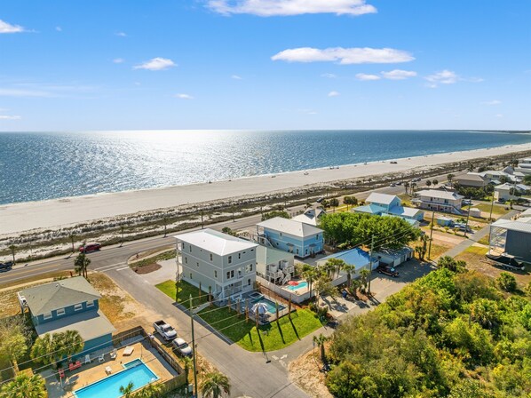 A coastal residential area with houses, a beach, and a clear sky. - Sandy Feet Retreat | 8BR | Gulf View Escape! Private Pool & Spa! Walk to Beach! (mexico beach)