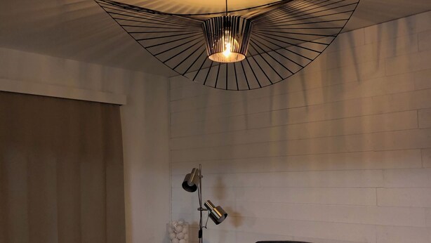 A modern living room with a unique ceiling light fixture, a black leather sofa, a wooden coffee table, and a floor lamp. - Quiet gîte between hills and forest. Sauna and pets welcome. (Bièvre)