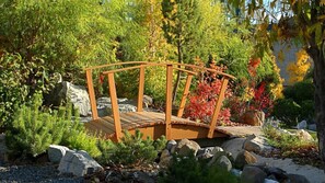 A wooden bridge in a garden with rocks and various plants. - Lake Tahoe 2BR Lodge Villa – Fireplace, Full Kitchen & Steps to Incline Village (Incline Village)