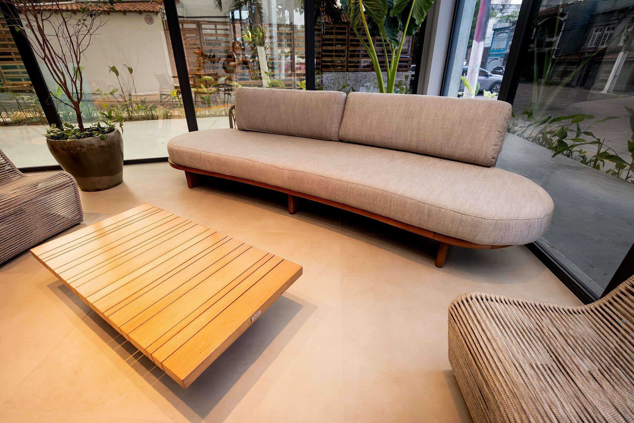 Een modern interieur met een beige bank, een houten salontafel en rieten stoelen.