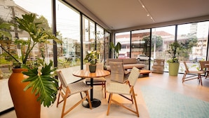 Un intérieur moderne avec une table ronde en bois, des chaises en osier et une grande plante en pot.