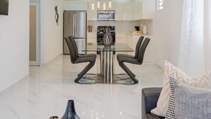 A modern kitchen with stainless steel appliances, a dining area with two chairs, and a marble floor. - La Casa Blanca [Unit #1 Machete] (Carolina)