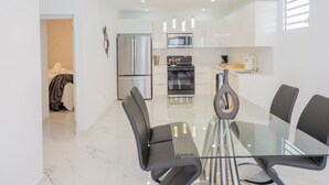A modern kitchen with stainless steel appliances, a glass dining table, and black chairs. - La Casa Blanca [Unit #1 Machete] (Carolina)