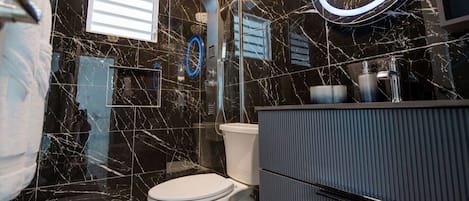 A modern bathroom with a toilet, vanity, and a shower enclosure.