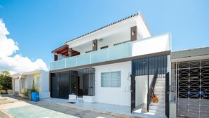 A modern two-story house with a balcony, a garage with a car, and a staircase leading to the upper floor. - La Casa Blanca [Unit #1 Machete] (Carolina)