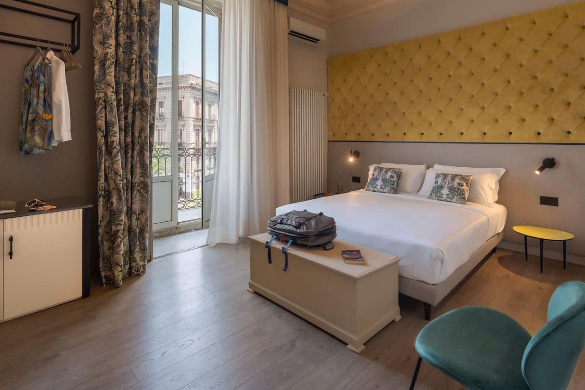 Ein Hotelzimmer mit Bett, Schreibtisch, Stuhl und Blick auf die Stadt.