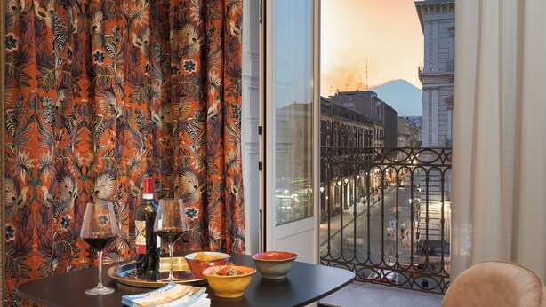 Een balkon met een eettafel, compleet met wijnglazen, kommen en een boek.