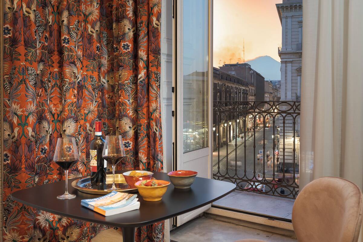 Ein Balkon mit Esstisch, Weingläsern, Schüsseln und einem Buch.