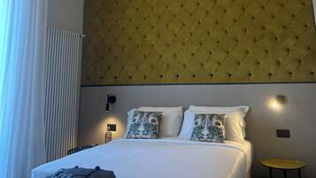 Habitació d'hotel amb llit, una taula de nit, una maleta i una taula petita groga.