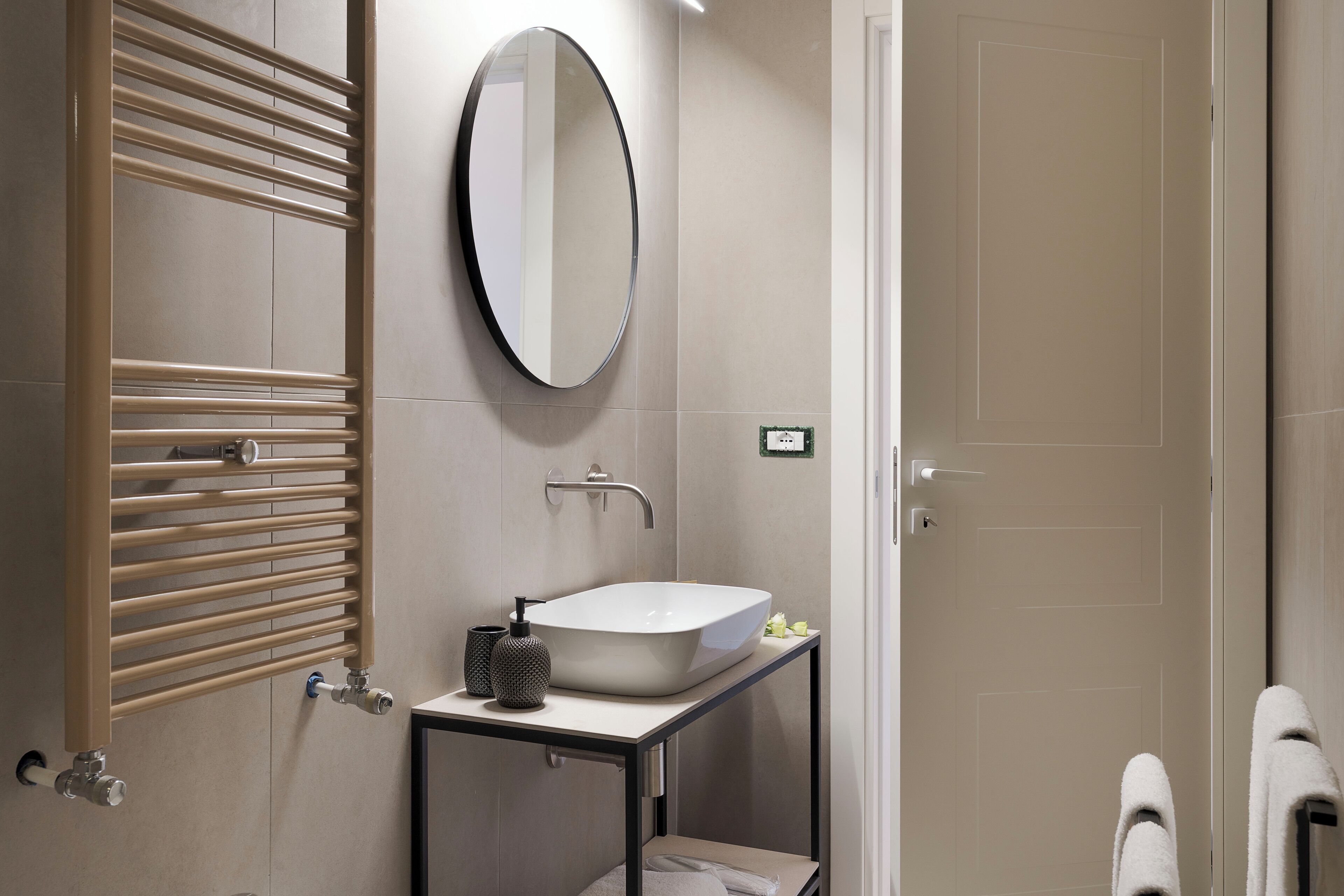 A modern bathroom with a bathtub, a sink, a mirror, and a towel rack.